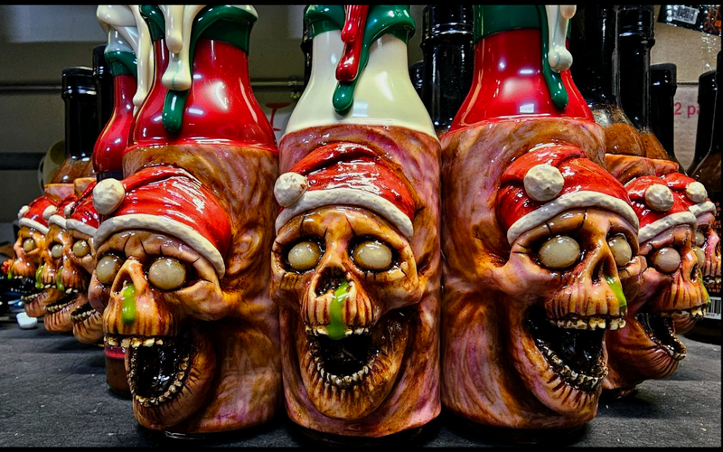 A limited edition series of Christmas art bottles with skull designs, resin sealed, decorated with red and green accents, and signed and numbered by the artist.